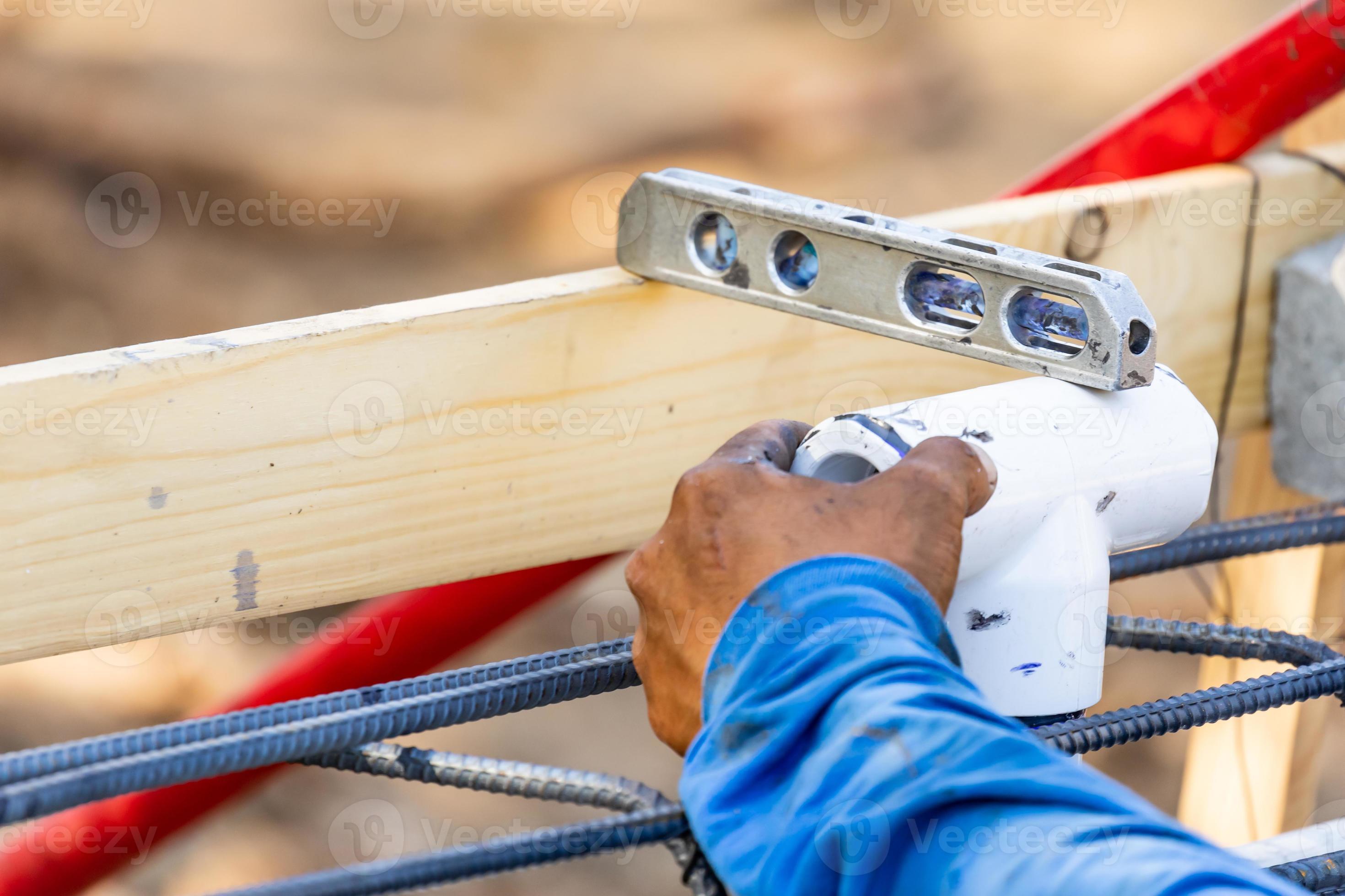 Plumber Using Level While Installing PVC Pipe At Construction Site