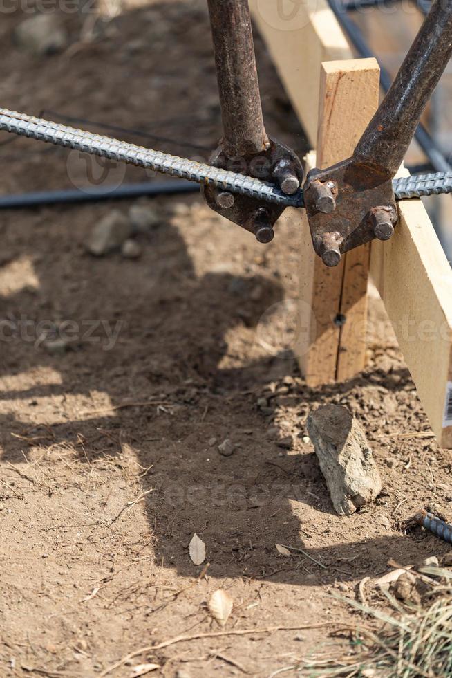 Worker Using Tools To Bend Steel Rebar At Construction Site photo
