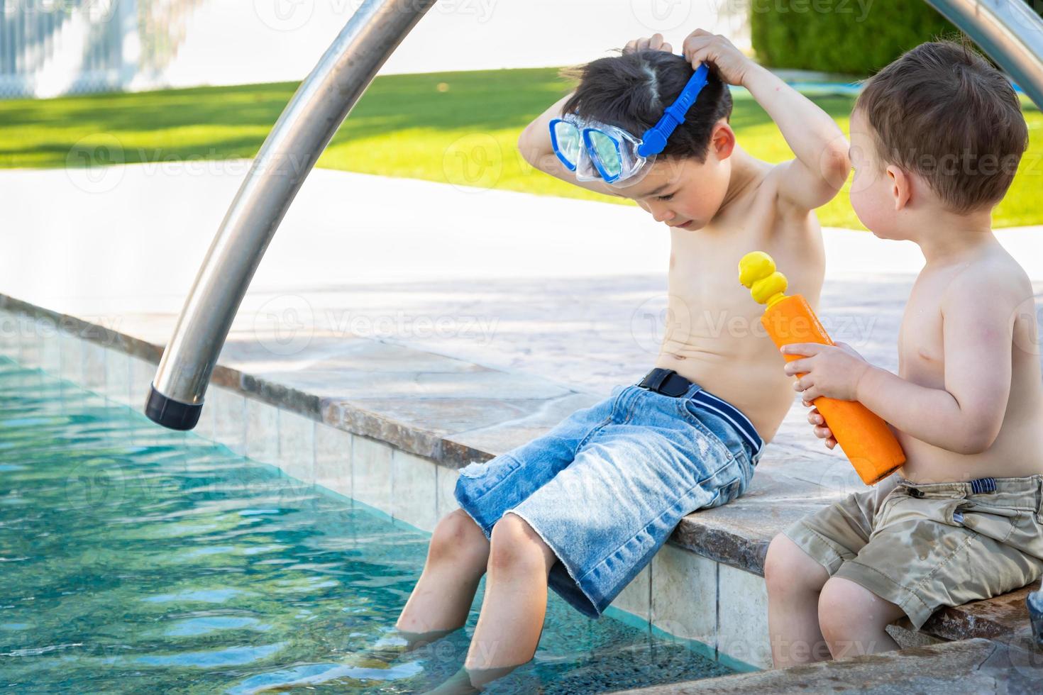 Young Mixed Race Chinese and Caucasian Brothers Wearing Swimming Goggles Playing At The Pool photo