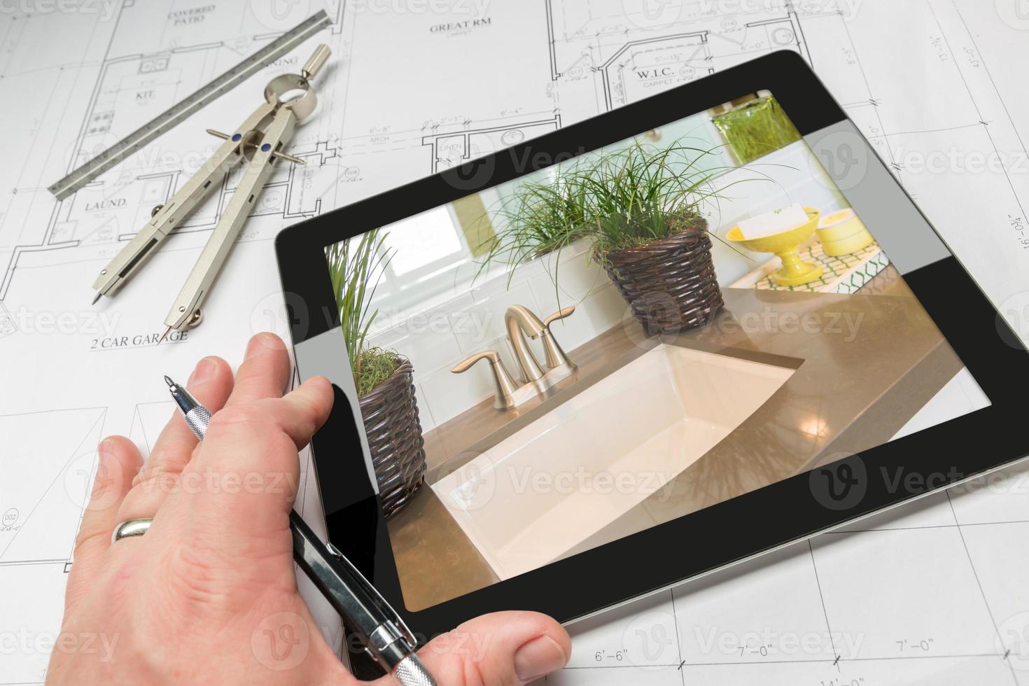 Hand of Architect on Computer Tablet Showing Bathroom Details Over House Plans photo