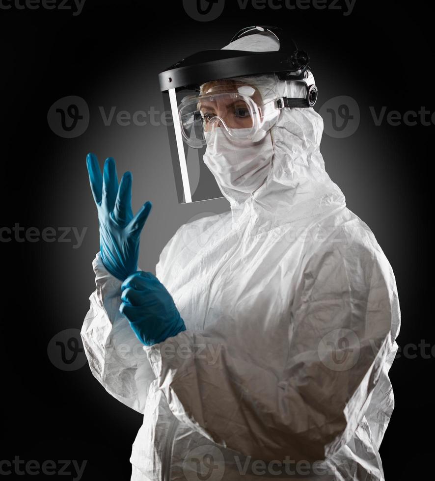 Female Medical Worker Wearing Protective Face Mask and Gear Against Dark Background photo