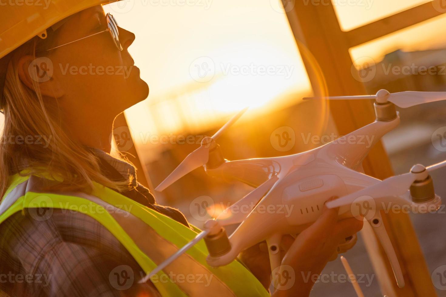 Sistema de aeronaves no tripuladas hembra piloto de drones quadcopter sosteniendo drones en el sitio de construcción foto