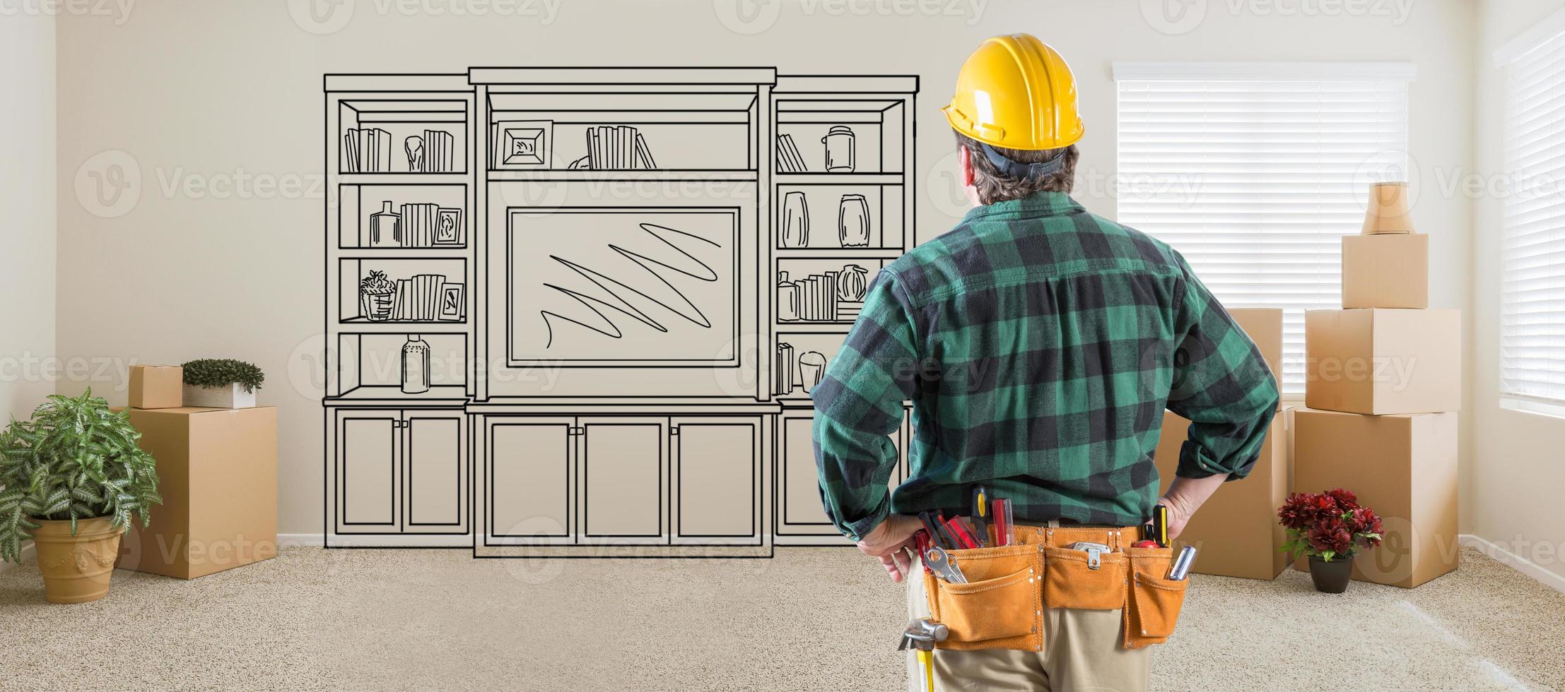 Contractor Inside Room With Boxes Facing Entertainment Unit Drawing On Wall photo
