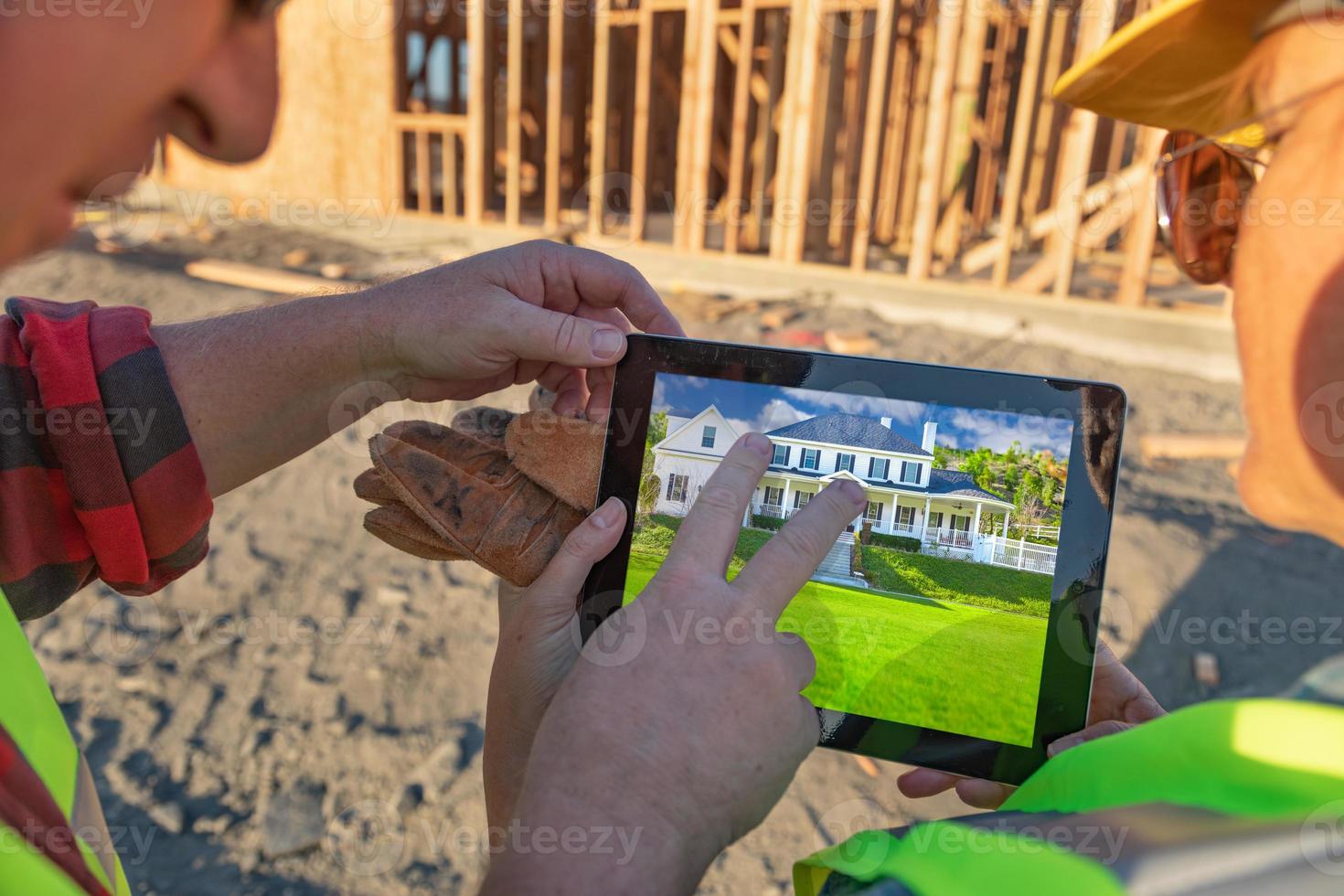 Male and Female Construction Workers Reviewing House on Computer Pad at Construction Site photo