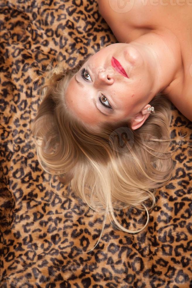 Beautiful Blonde Woman Poses on Leopard Blanket. photo
