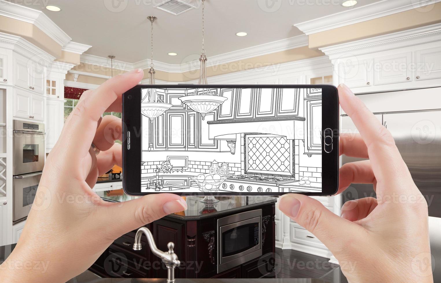Hands Holding Smart Phone Displaying Drawing of Kitchen Photo Behind