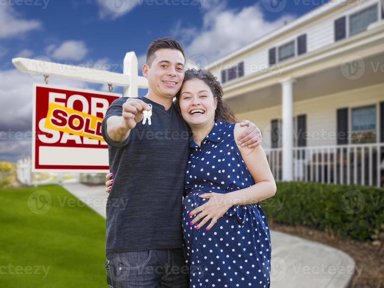 pareja hispana con llaves frente a casa y firma foto