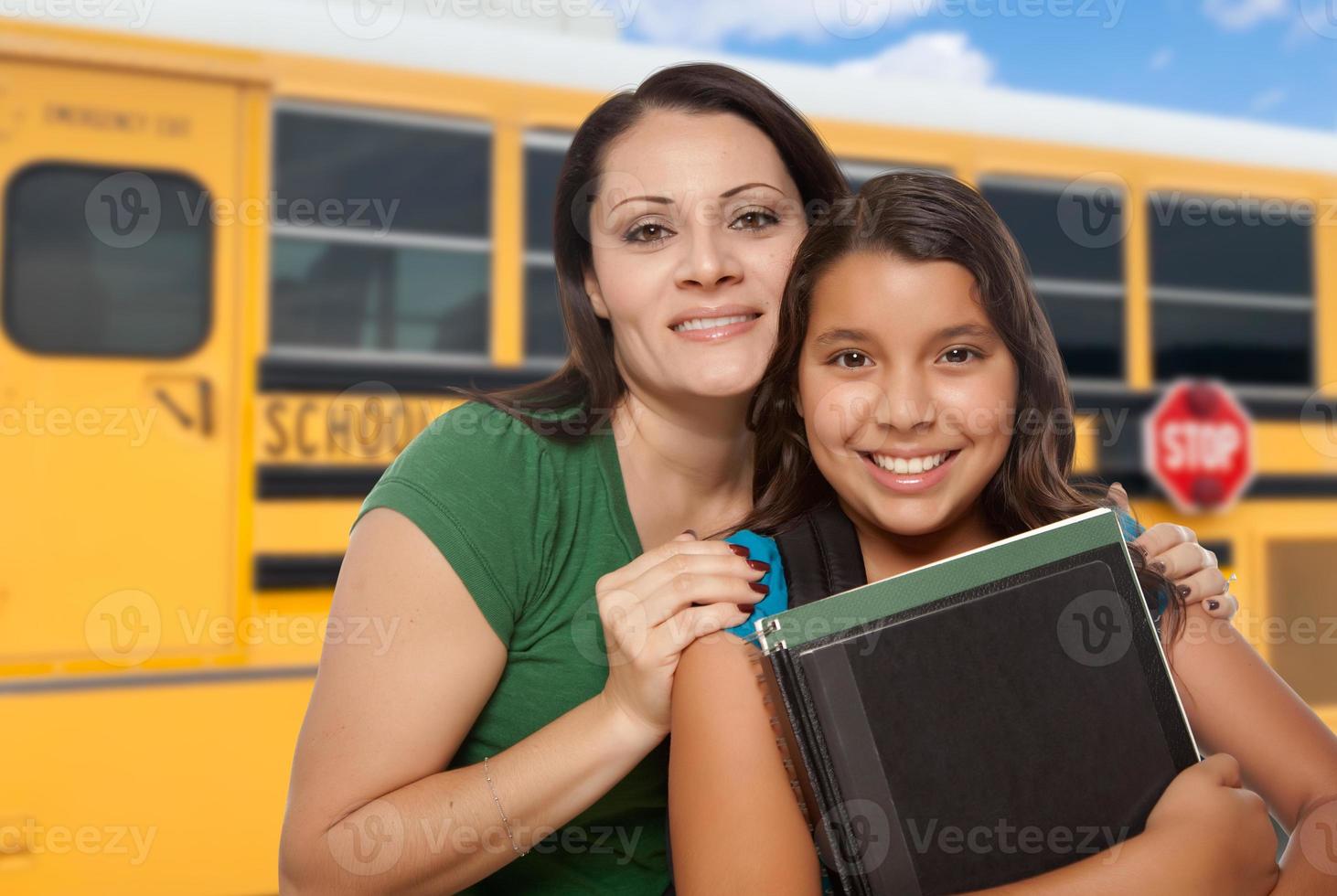 madre e hija hispanas cerca del autobús escolar. foto