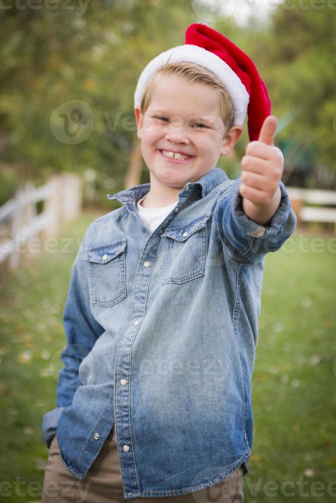 Young Boy Wearing Holiday Clothing Giving a Thumbs Up Outside photo