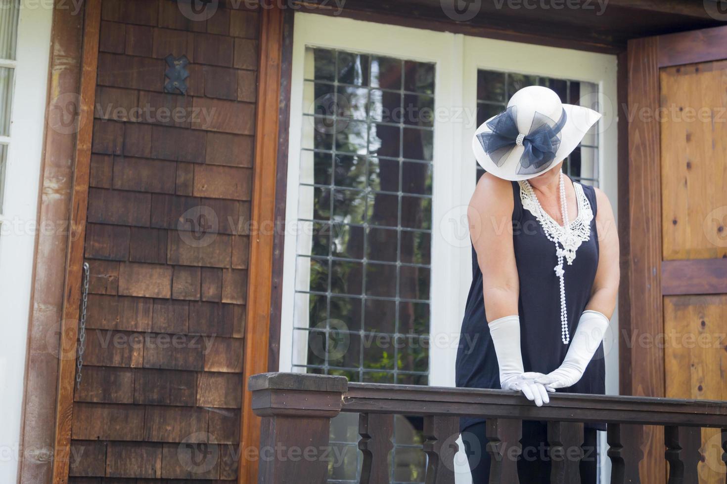 Attractive Woman in Twenties Outfit on Porch of Antique House photo