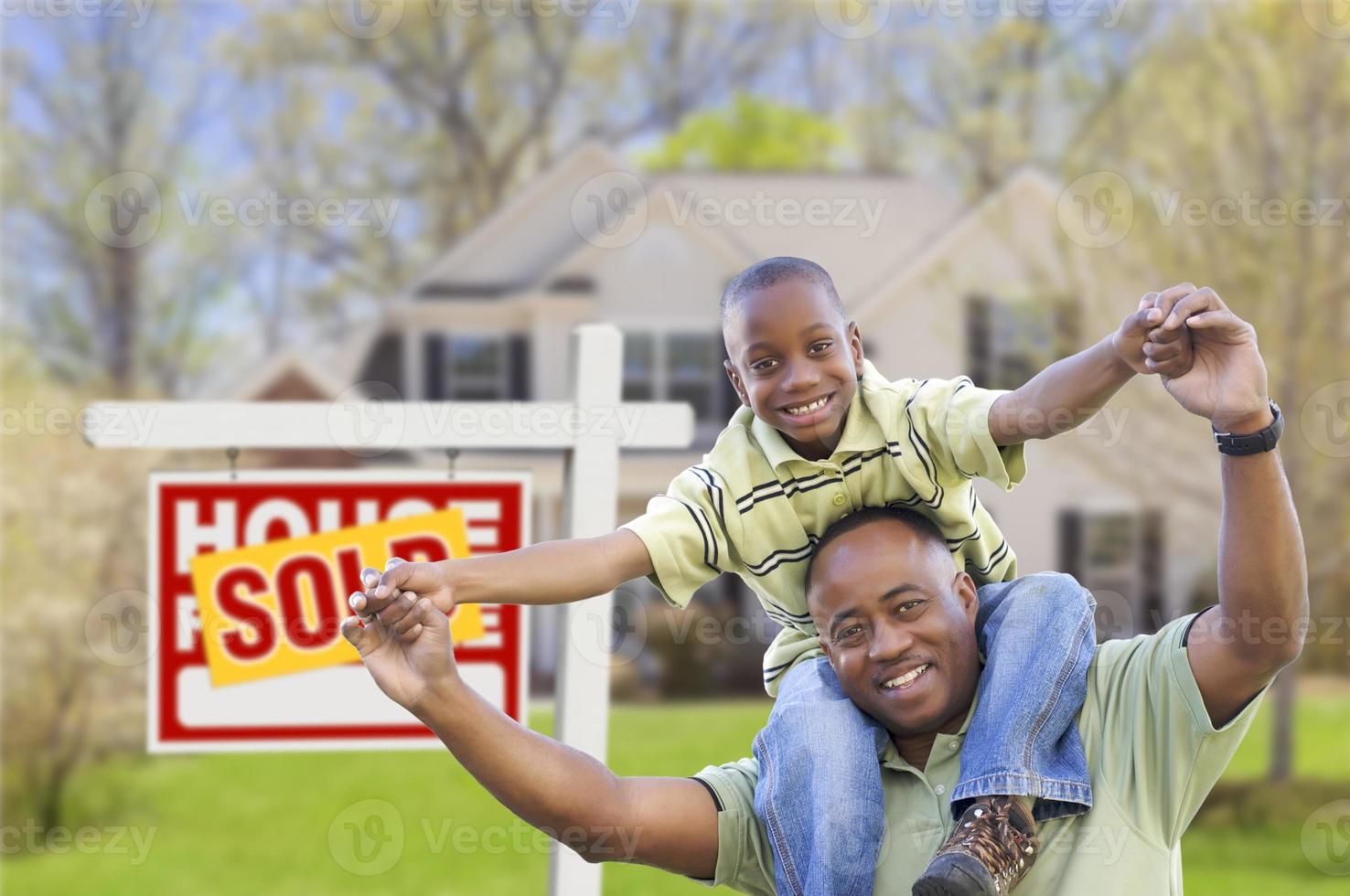 padre e hijo frente al letrero de bienes raíces y el hogar foto