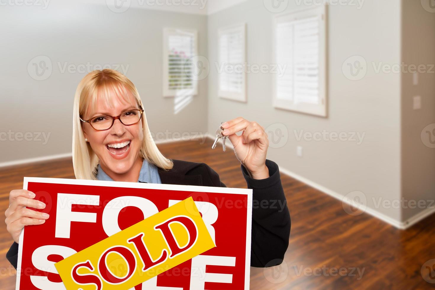 Woman with Sold For Sale Real Estate Sign and Keys In Empty Room of New House photo