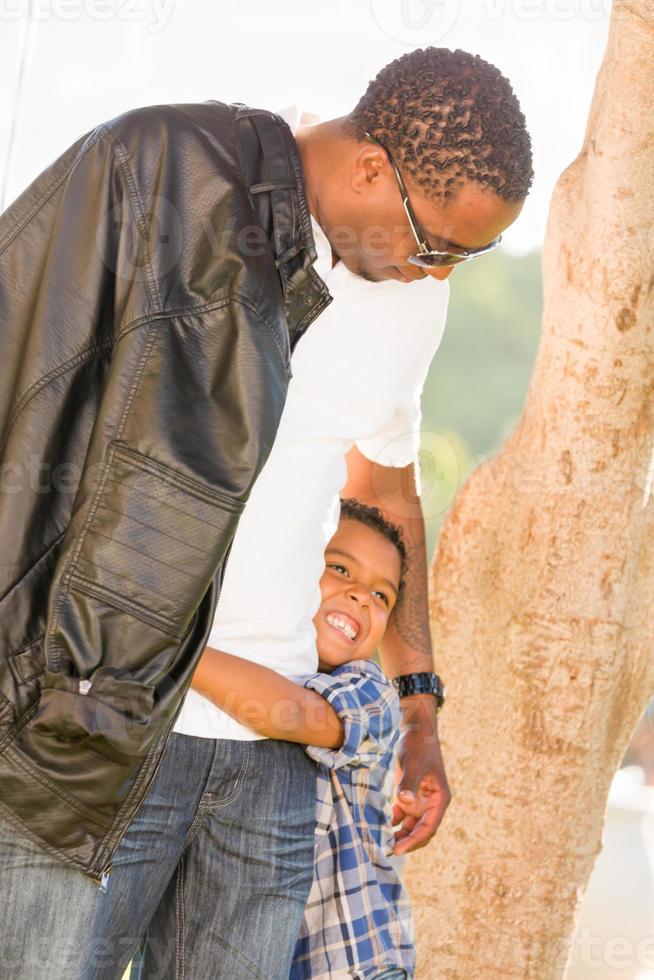 feliz padre afroamericano e hijo de raza mixta jugando en el parque foto