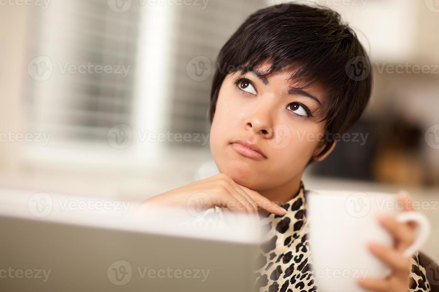 Pretty Mixed Race Woman Holding Cup Using Laptop photo