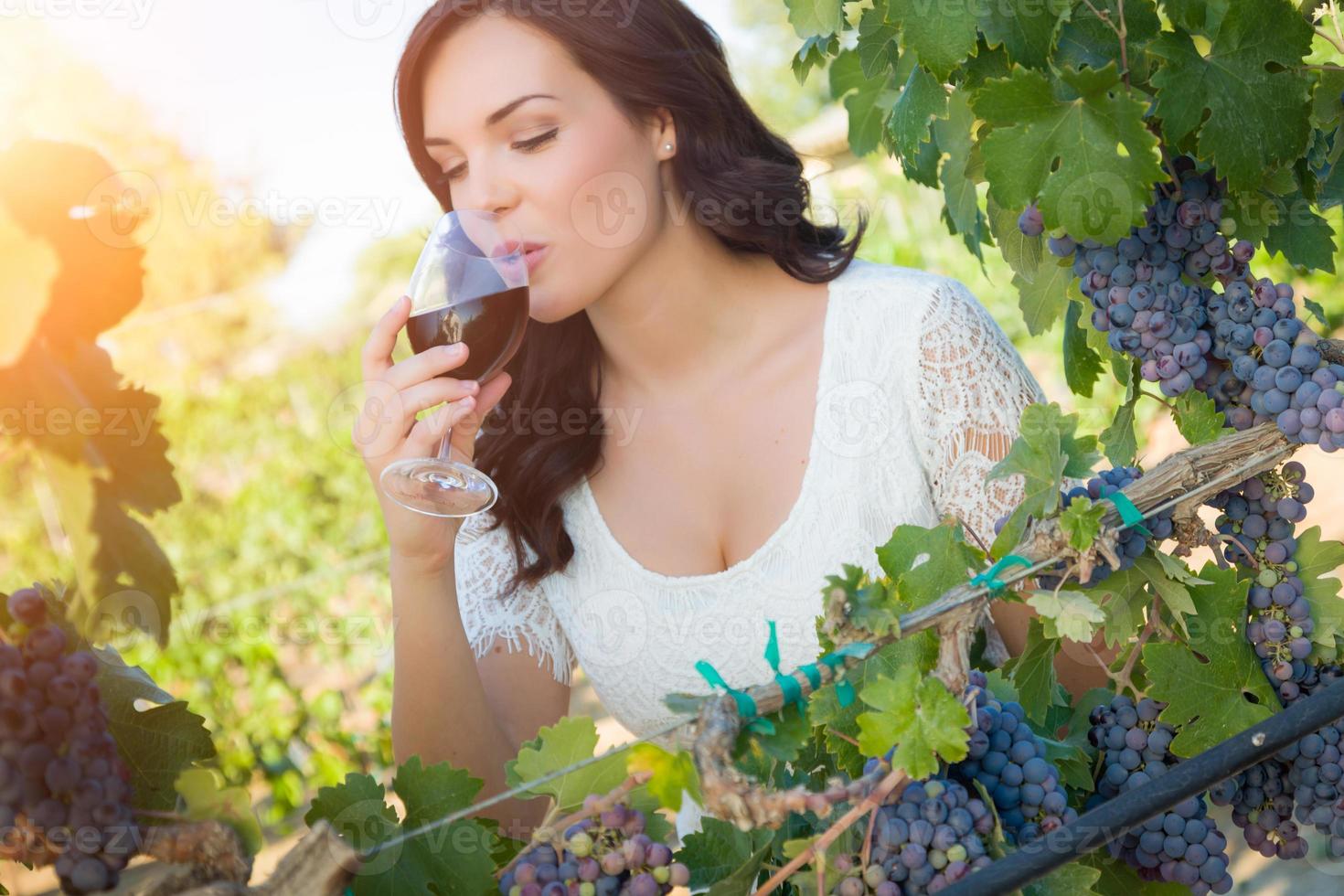 Beautiful Young Adult Woman Enjoying Glass of Wine Tasting In The Vineyard photo