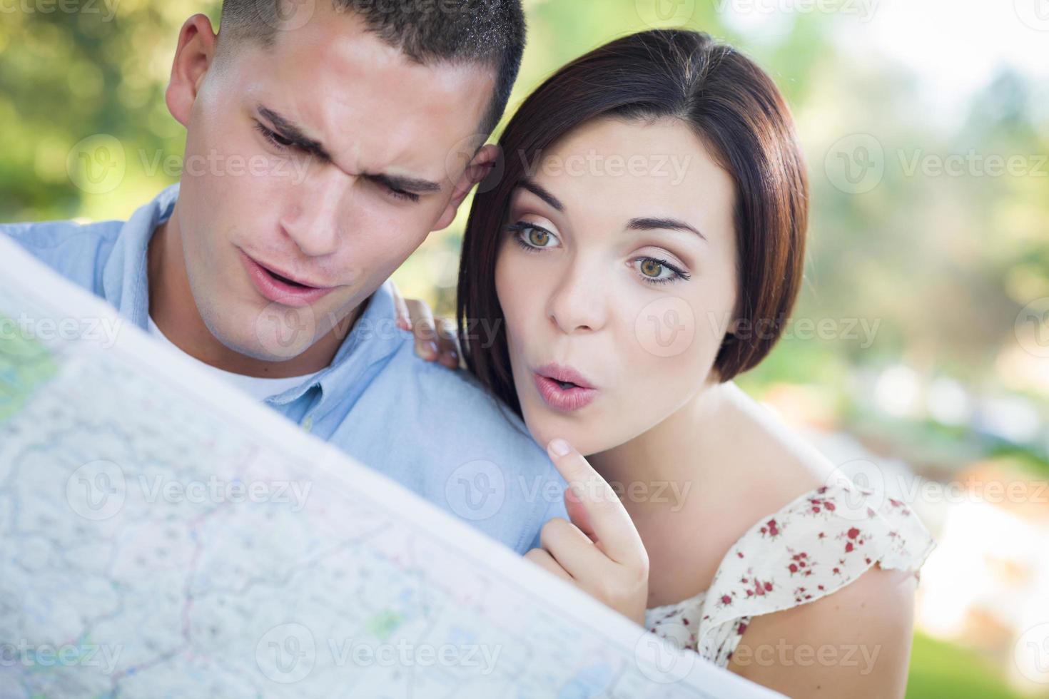 pareja de raza mixta mirando el mapa afuera juntos foto