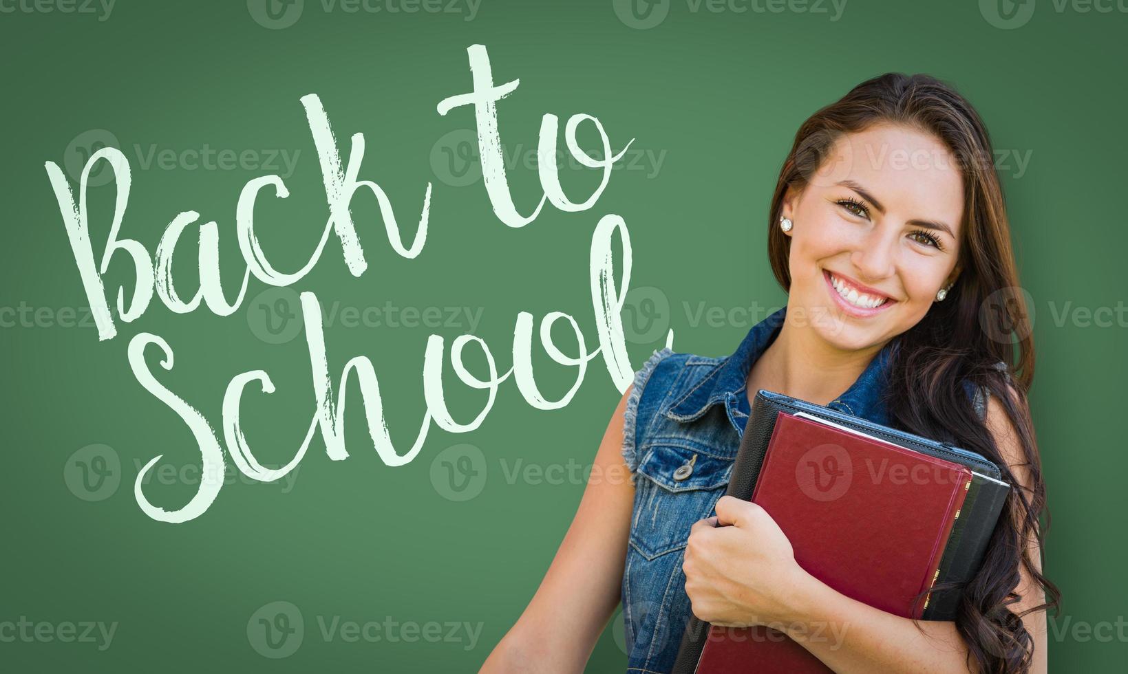 Back To School Written On Chalk Board Behind Mixed Race Young Girl Student Holding Books photo