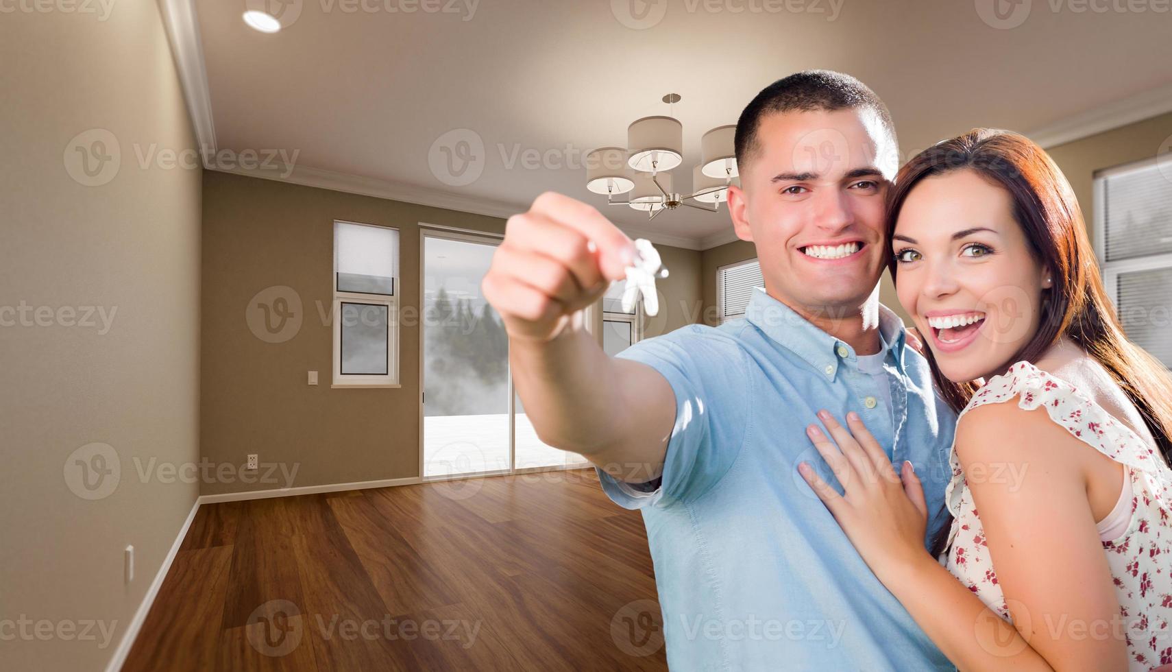 Young Military Couple with House Keys In Empty Room of New Home. photo