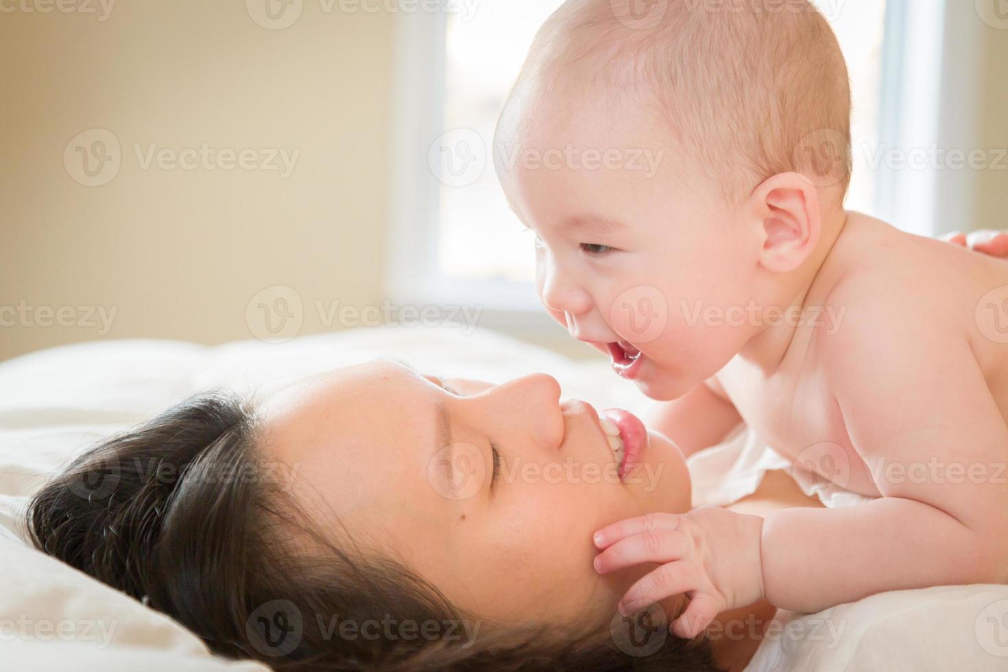 Mixed Race Chinese and Caucasian Baby Boy Laying In Bed with His Mother photo