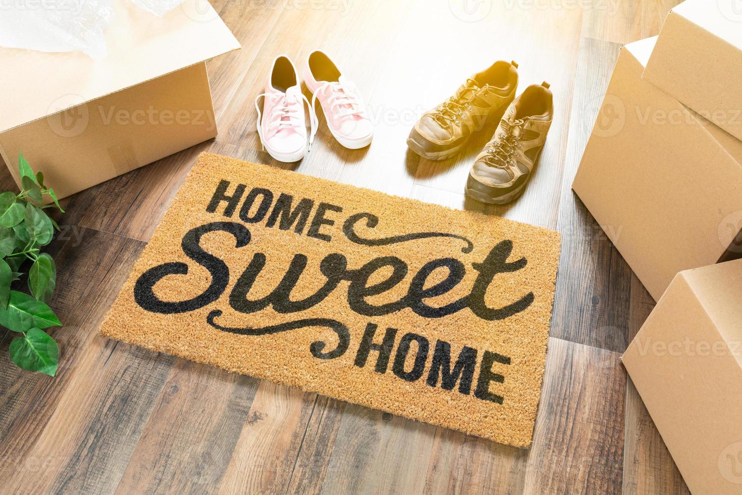 Home Sweet Home Welcome Mat, Moving Boxes, Women and Male Shoes and Plant on Hard Wood Floors photo