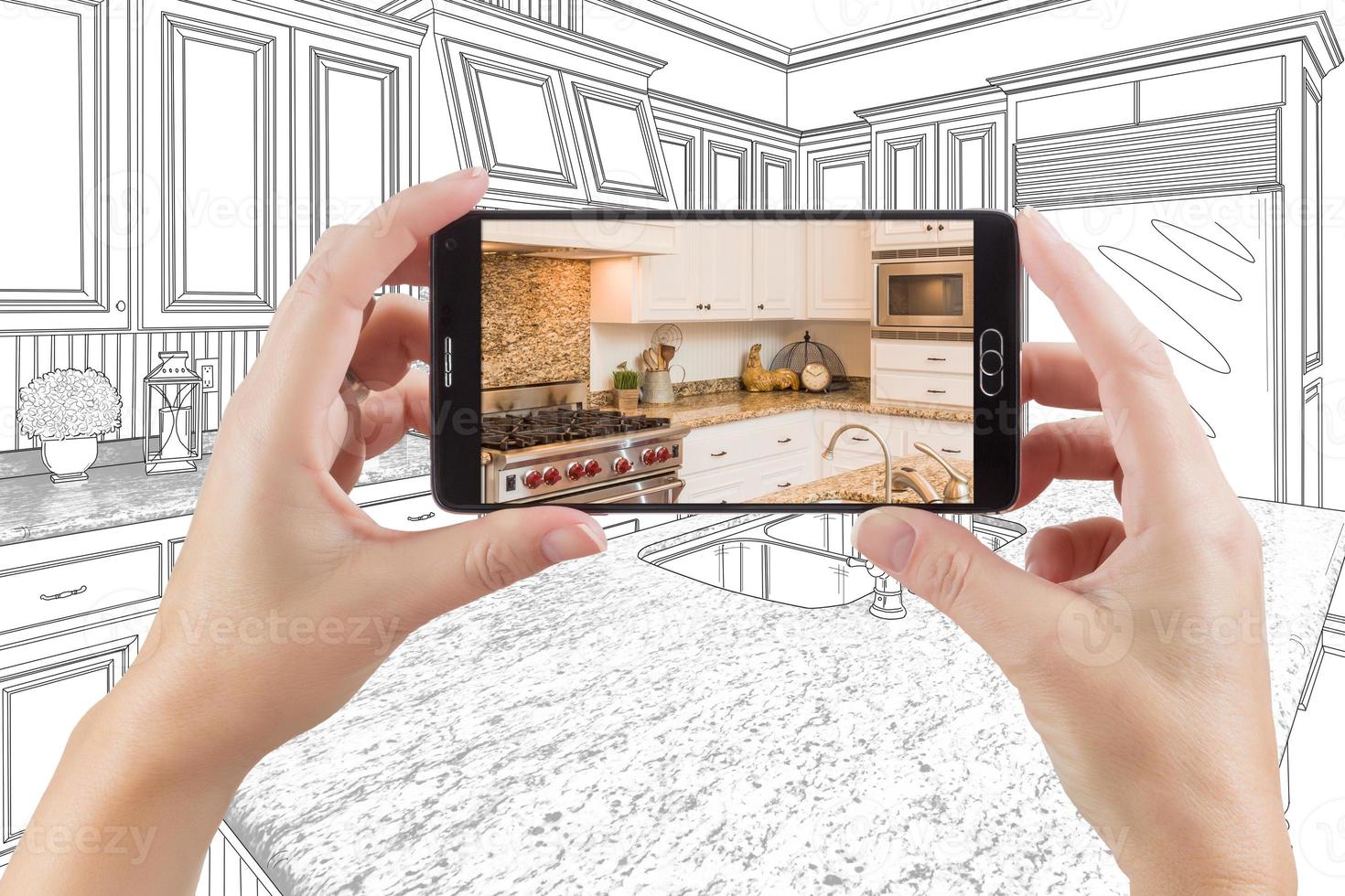 Hands Holding Smart Phone Displaying Photo of Kitchen Drawing Behind