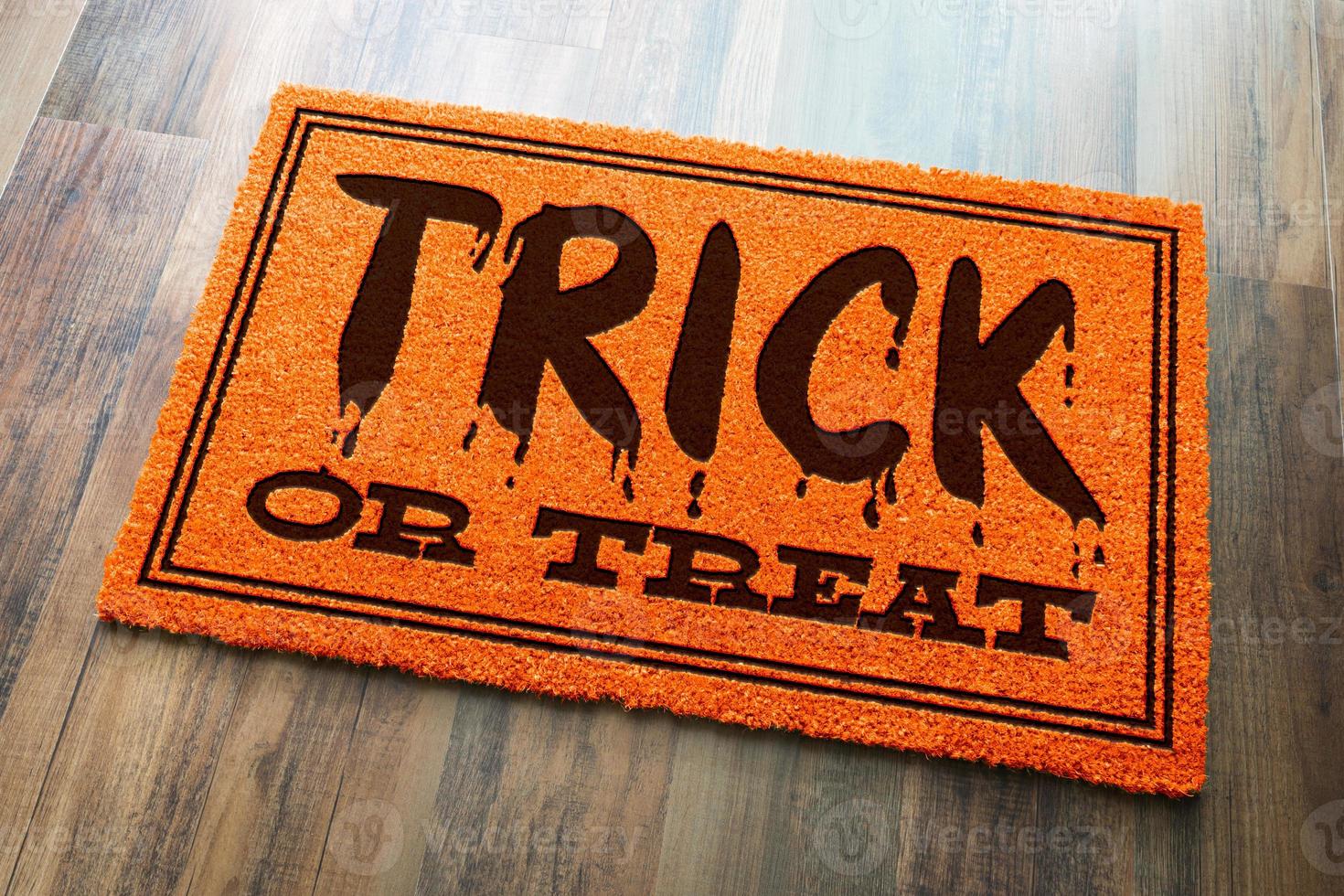 Trick Or Treat Halloween Orange Welcome Mat On Wood Floor Background photo