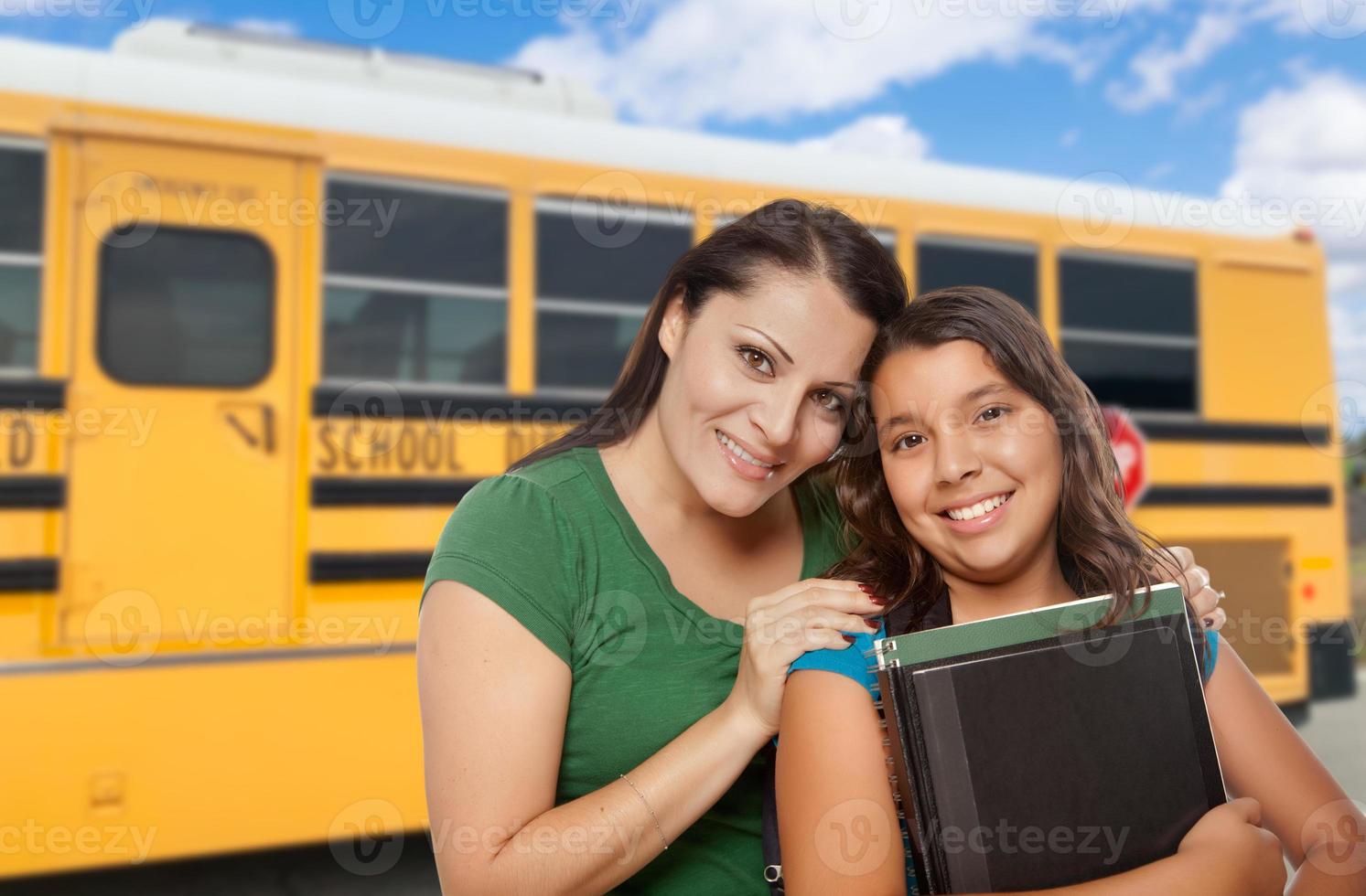 madre e hija hispanas cerca del autobús escolar. foto