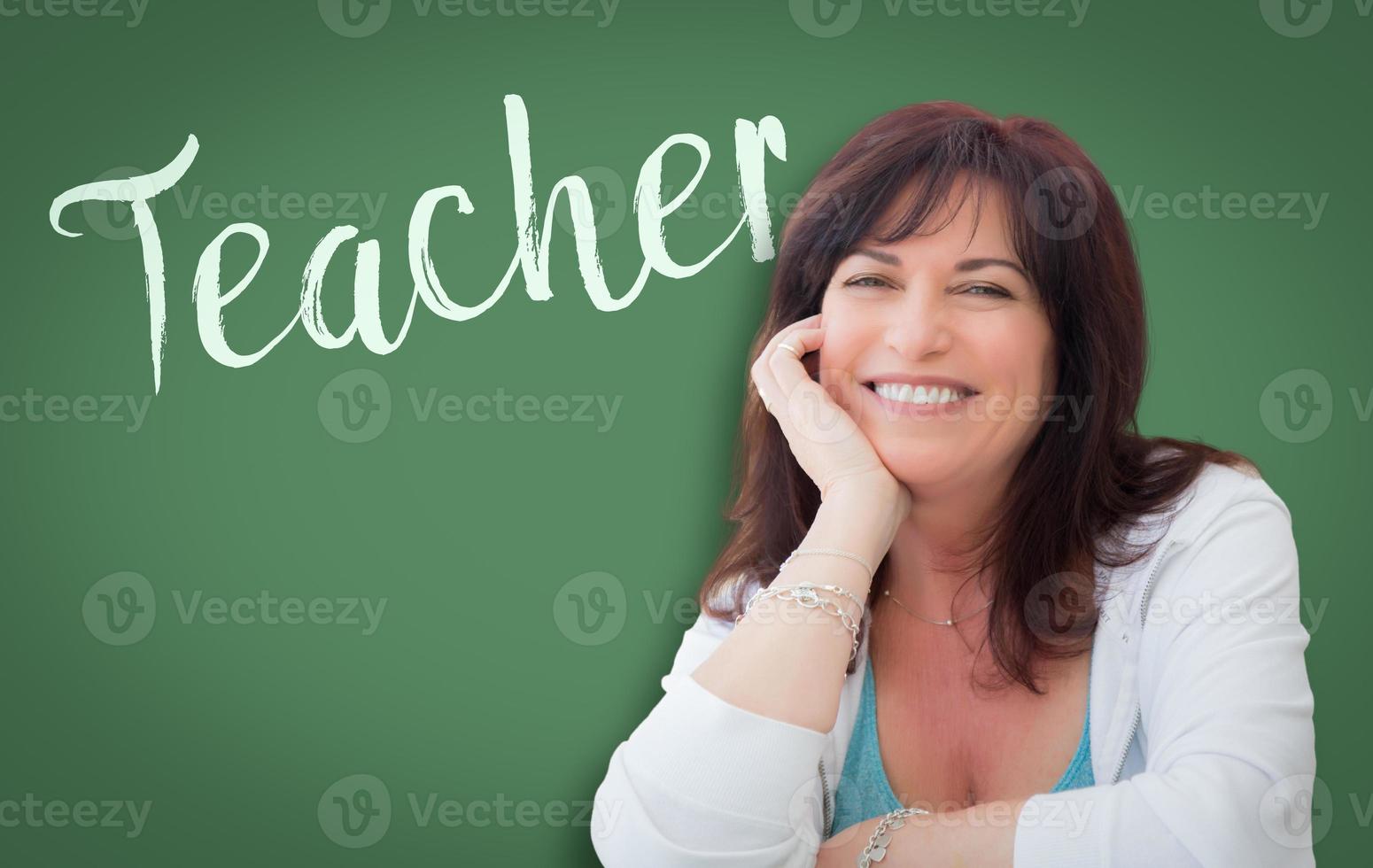 Teacher Written On Green Chalkboard Behind Smiling Middle Aged Woman photo