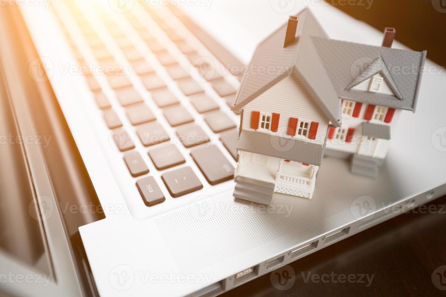 Miniature House And Laptop Computer Resting on Desktop. photo