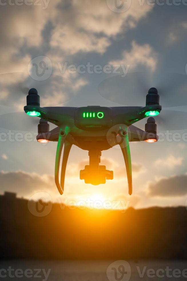 Silhouette of Unmanned Aircraft System Quadcopter Drone In The Air At Sunrise photo
