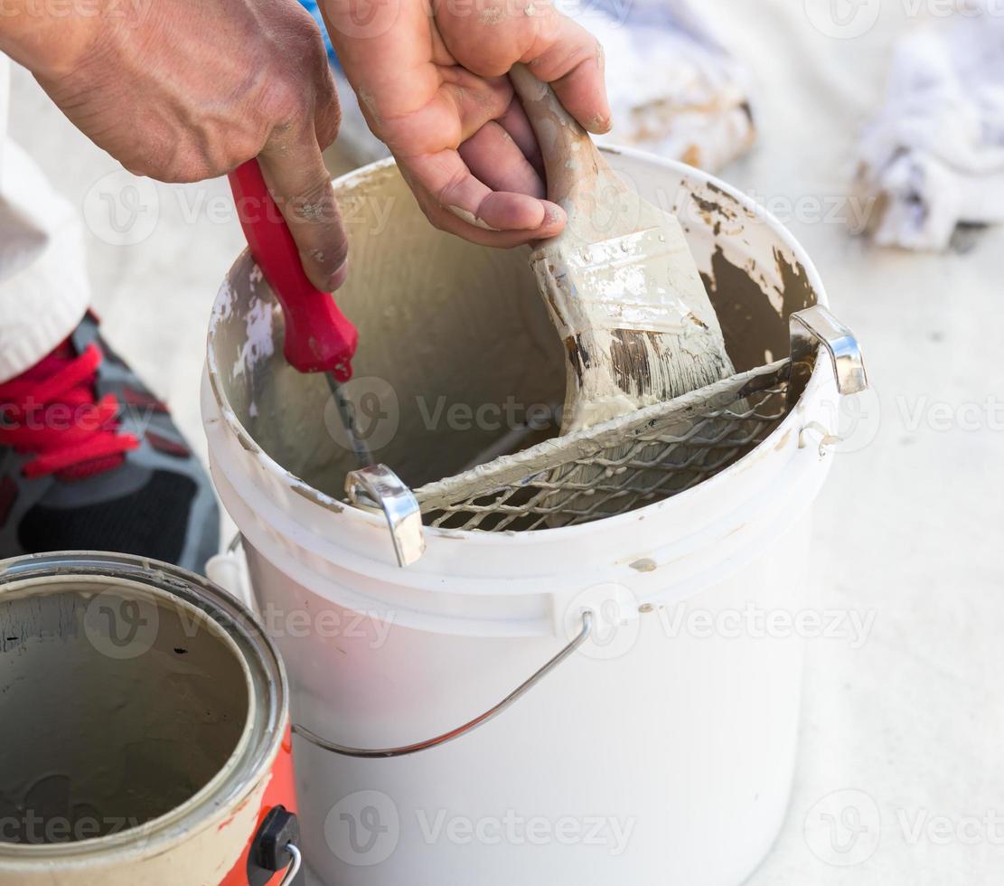 Professional Painter Loading Paint Onto Brush From Bucket photo
