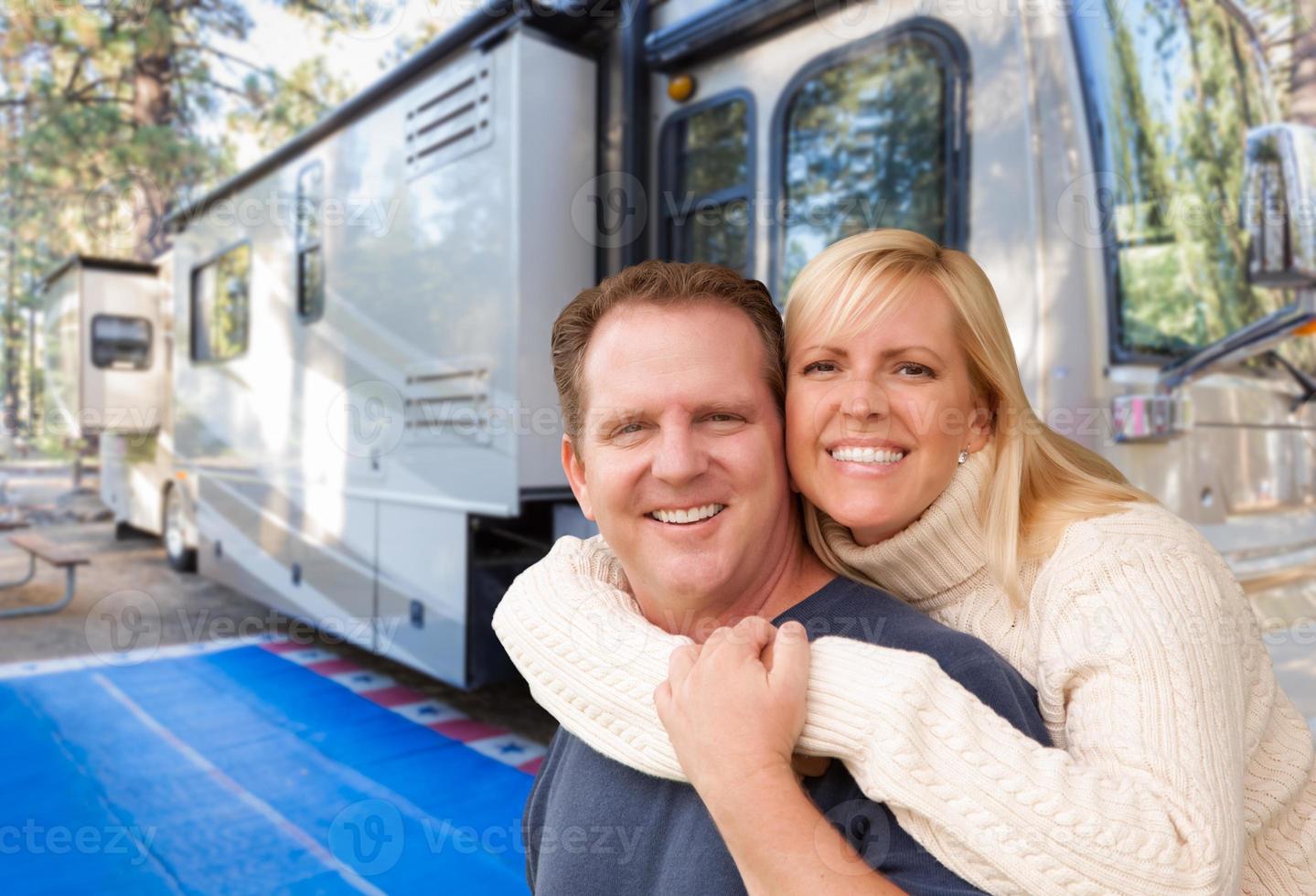 Happy Caucasian Couple In Front of Their Beautiful RV At The Campground. photo