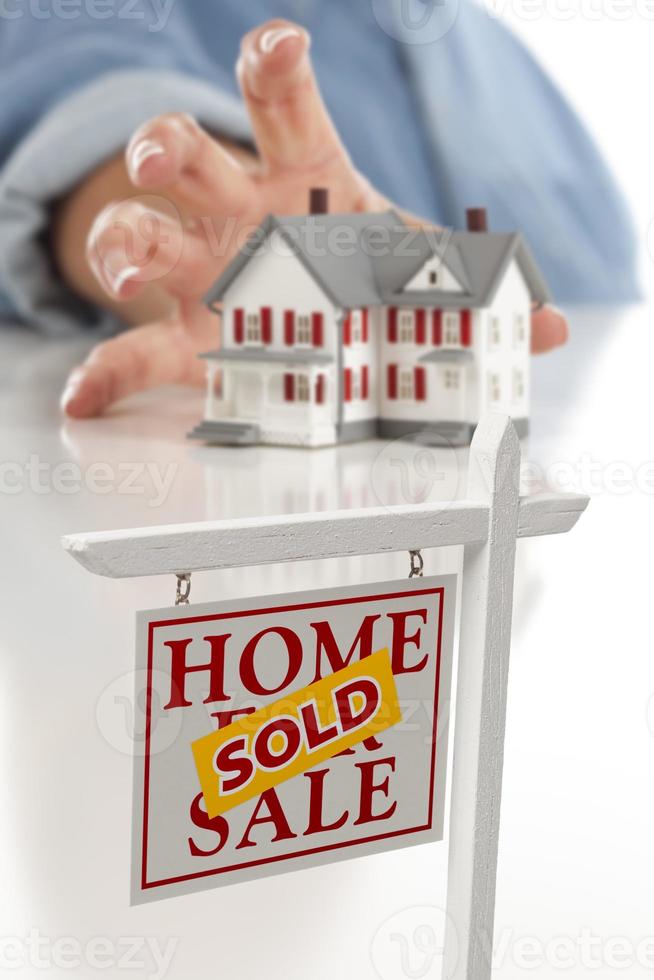 Sold Real Estate Sign in Front, Woman Reaching for House photo