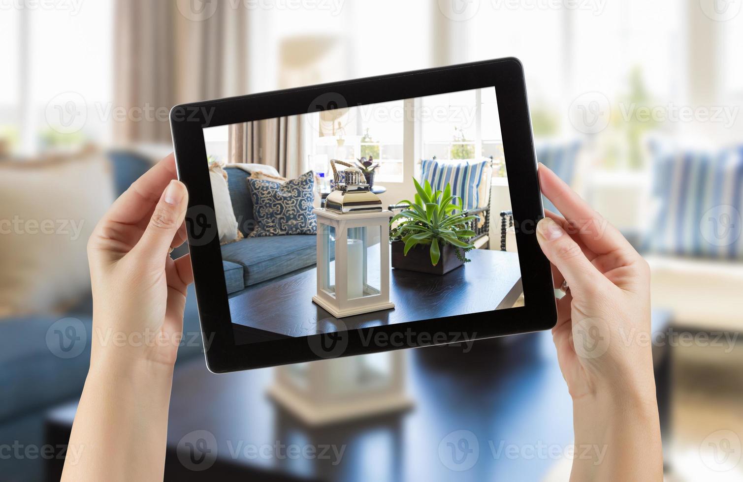 manos femeninas sosteniendo una tableta de computadora en la habitación con una foto en la pantalla.