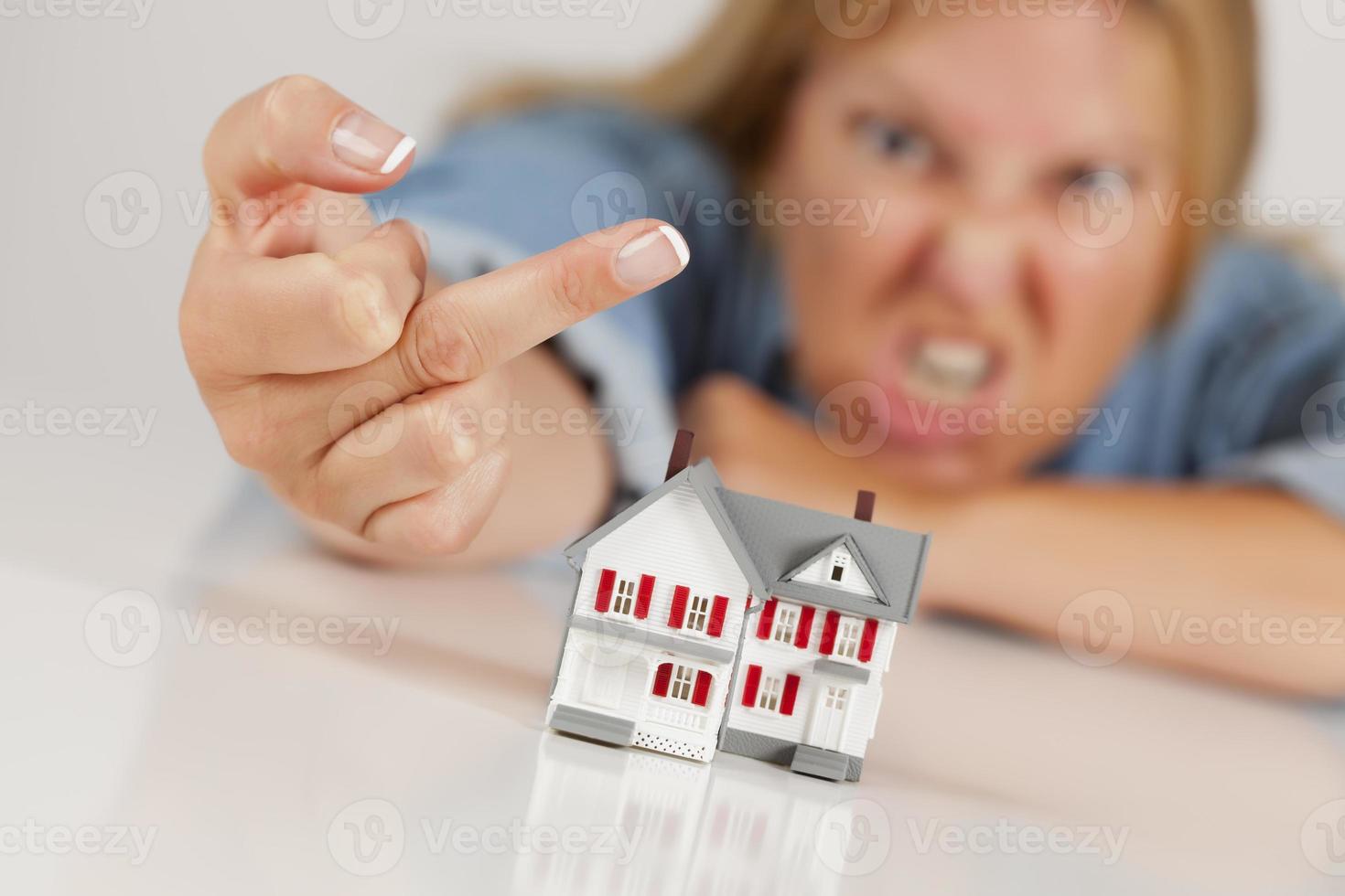 Angry Woman Flipping The Bird Behind Model Home on White photo