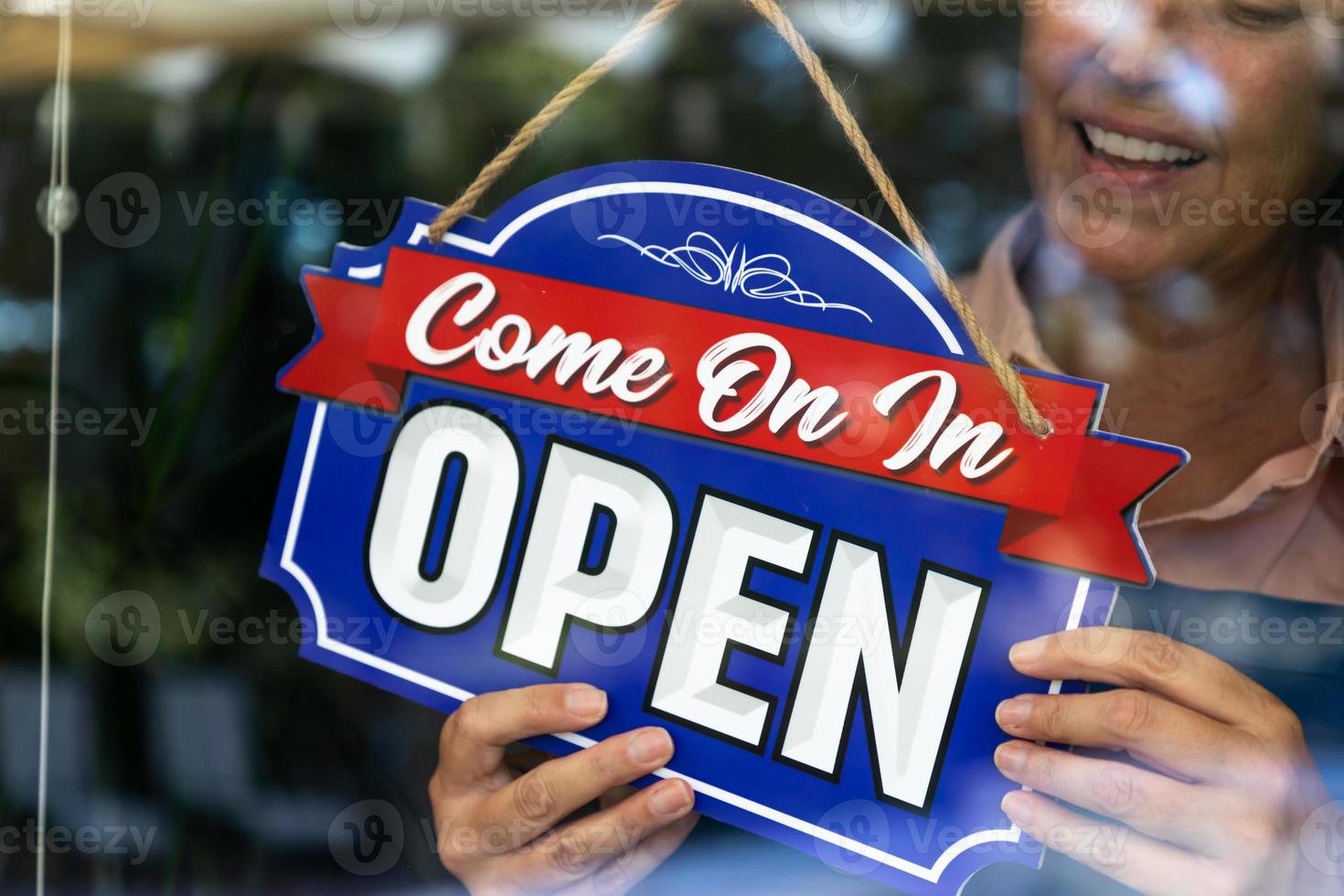 Happy Female Store Owner Turning Open Sign in Window photo