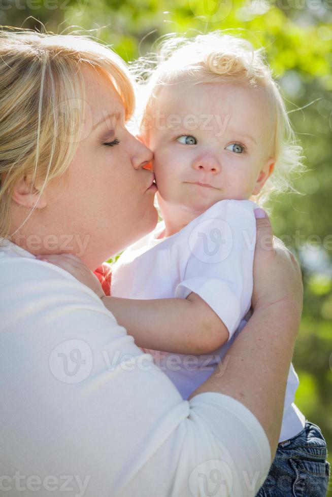 joven madre besando y sosteniendo a su adorable bebé foto