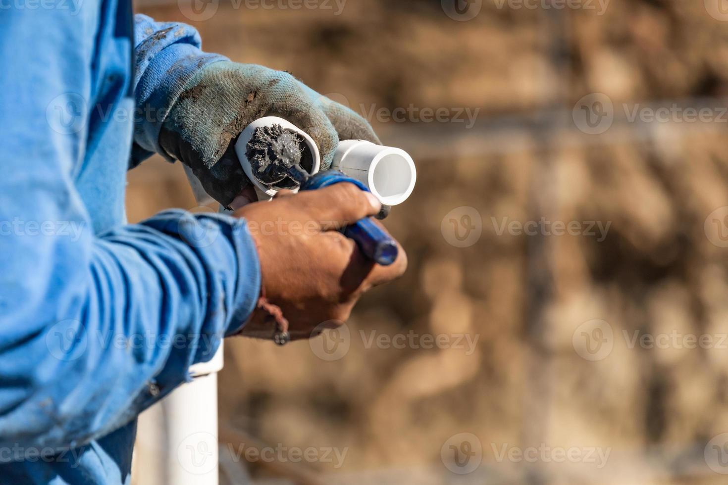 Plumber Applying Pipe Cleaner, Primer and Glue to PVC Pipe At Construction Site photo