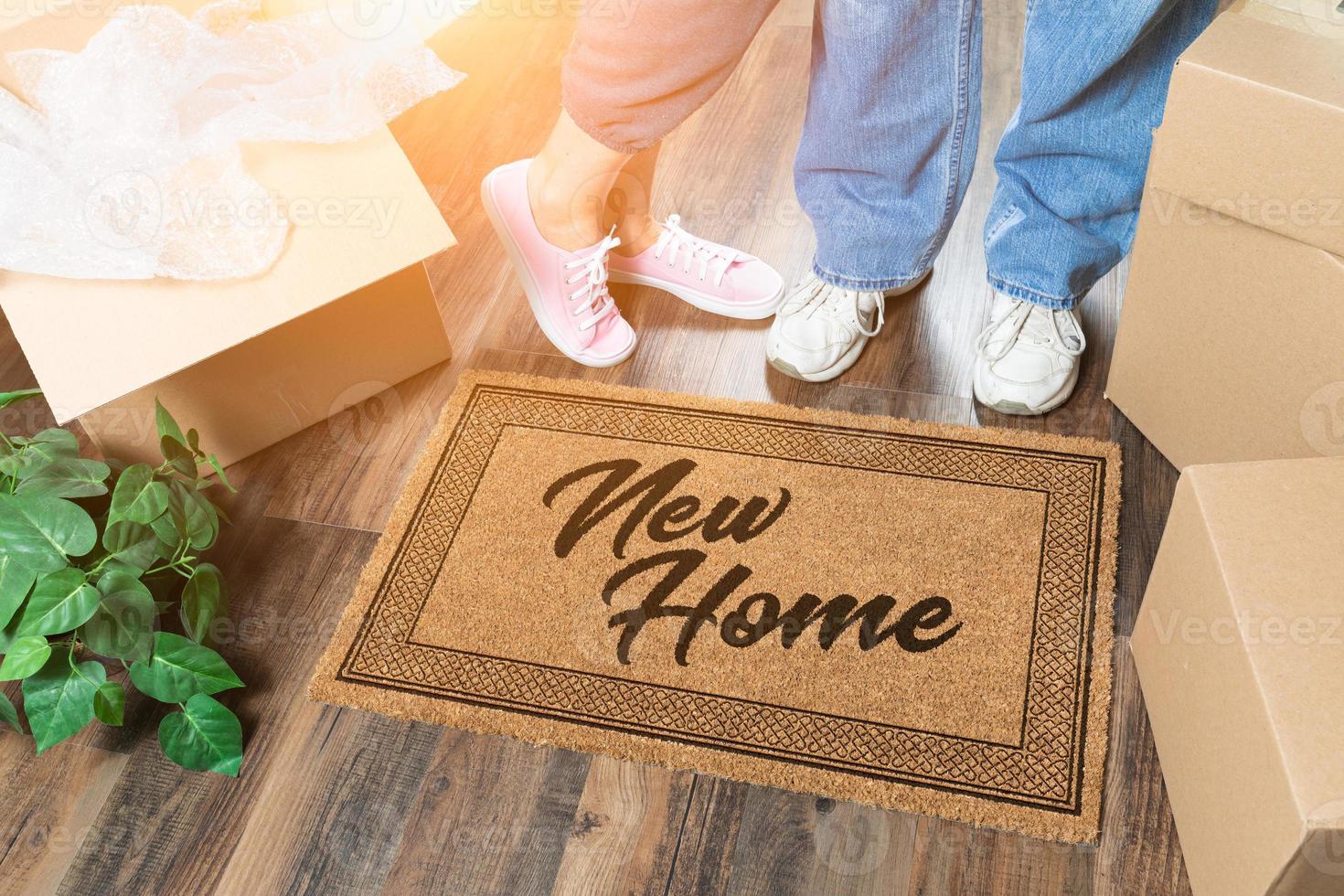 Man and Woman Unpacking Near New Home Welcome Mat, Moving Boxes and Plant photo