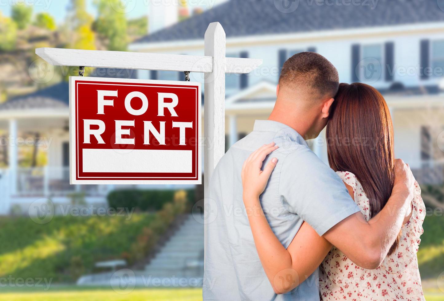 Military Couple Looking At House with For Rent Real Estate Sign In Front photo