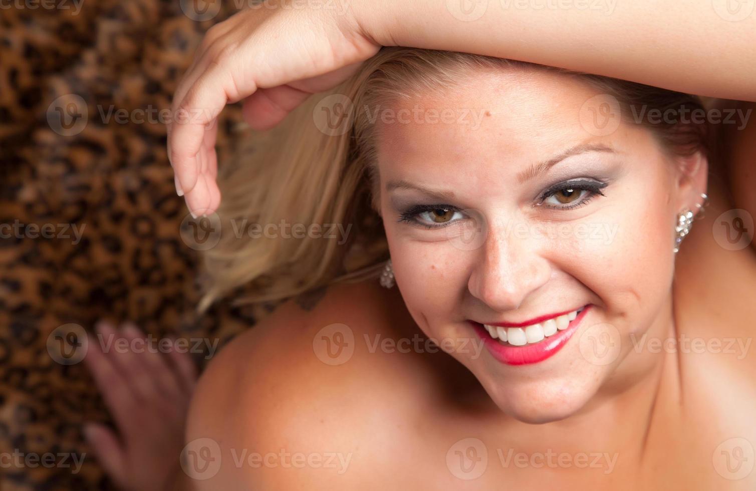 Beautiful Blonde Woman Poses on Leopard Blanket. photo