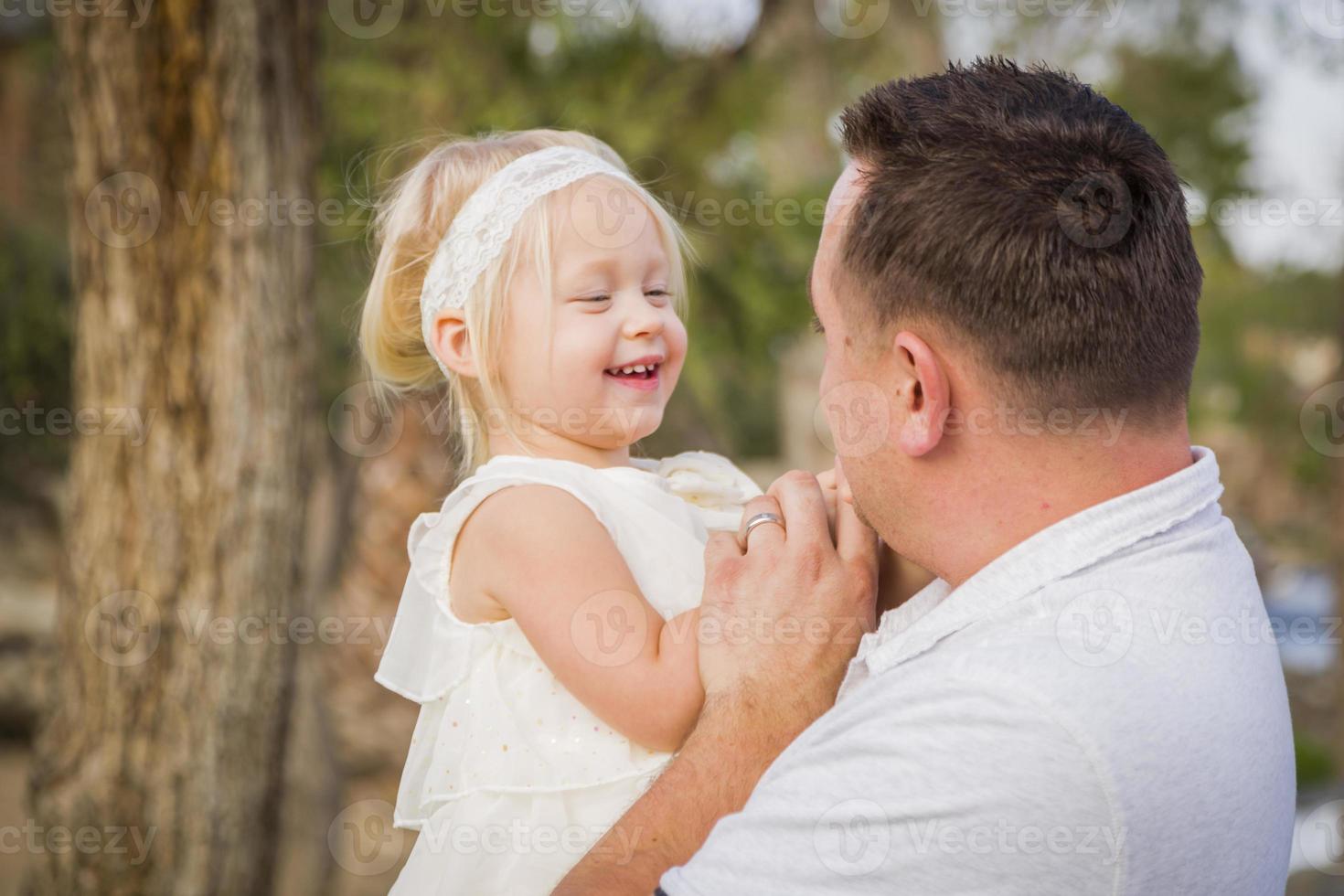 padre jugando con una linda niña afuera en el parque foto