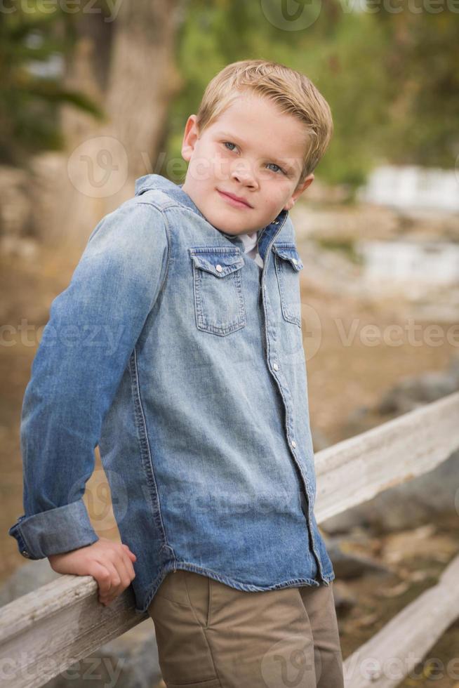 Handsome Young Boy Against Fence in Park photo