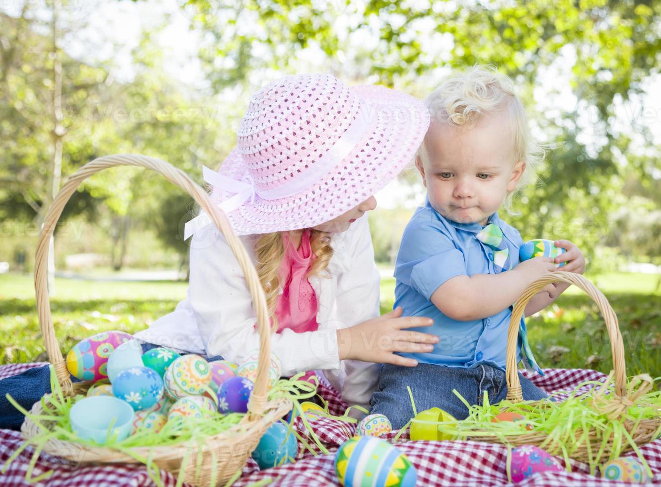 lindo joven hermano y hermana disfrutando de sus huevos de pascua afuera foto