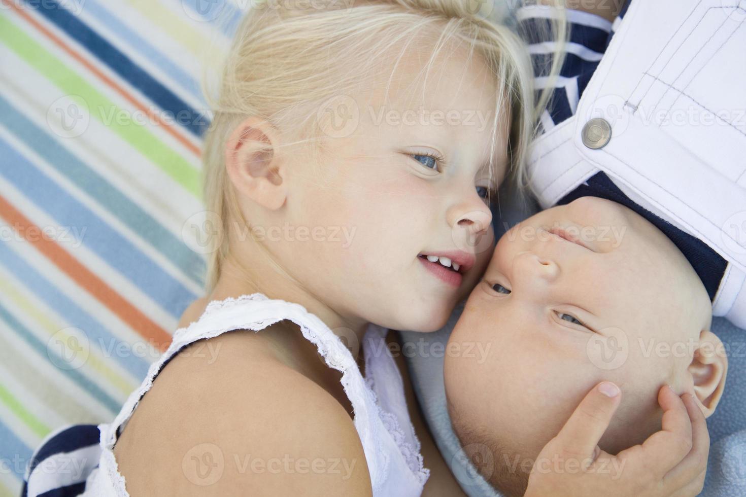 Little Sister Laying Next to Her Baby Brother on Blanket photo