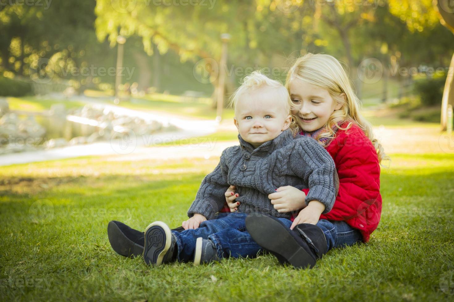 Little Girl with Baby Brother Wearing Coats at the Park photo