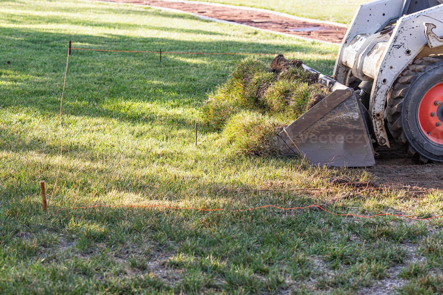 Small Bulldozer Removing Grass From Yard Preparing For Pool Installation photo