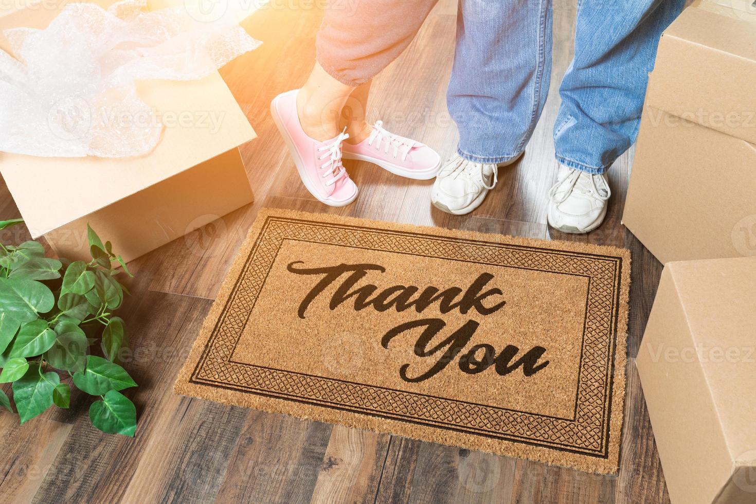 Man and Woman Unpacking Near Thank You Welcome Mat, Moving Boxes and Plant photo