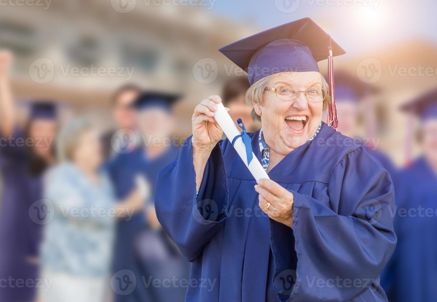 Happy Senior Adult Woman In Cap and Gown At Outdoor Graduation Ceremony. photo