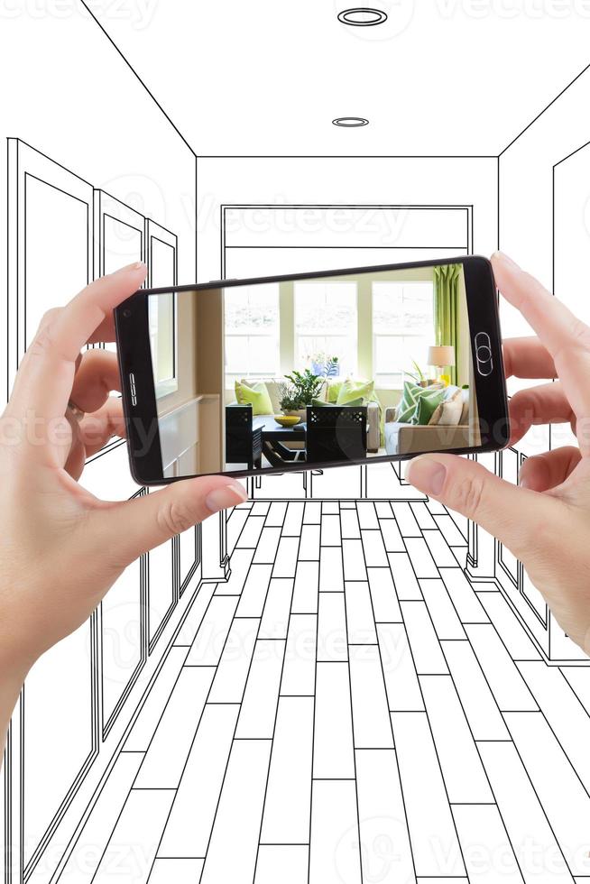 manos sosteniendo un teléfono inteligente que muestra una foto del dibujo del pasillo de la casa detrás